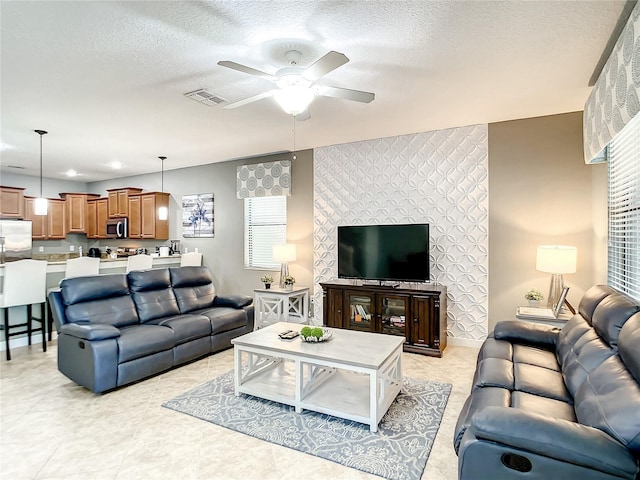 living room featuring ceiling fan and a textured ceiling