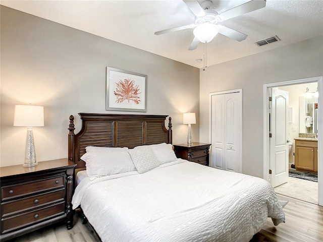 bedroom featuring ceiling fan, ensuite bath, a closet, and light hardwood / wood-style floors