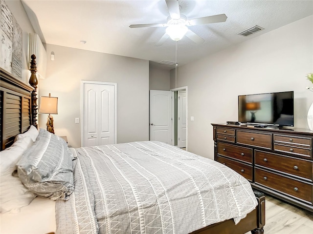 bedroom featuring a textured ceiling, ceiling fan, a closet, and light hardwood / wood-style floors