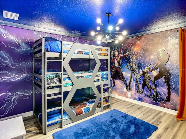 bedroom with a textured ceiling, hardwood / wood-style flooring, and a notable chandelier