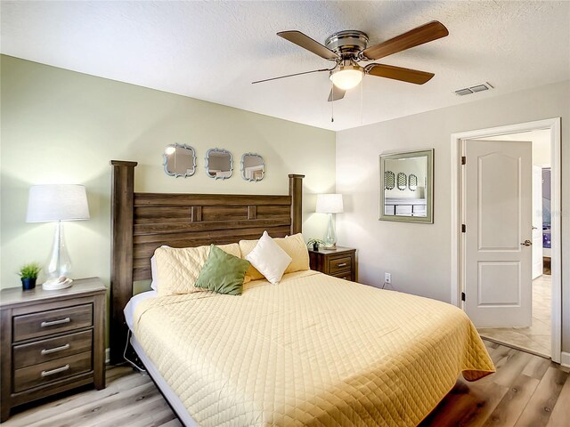 bedroom featuring light wood-type flooring, a textured ceiling, and ceiling fan