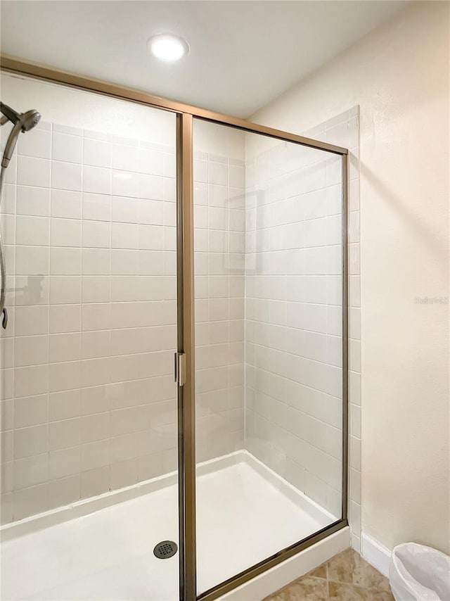 bathroom with a shower with shower door and tile patterned floors