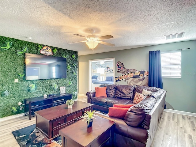 living room with ceiling fan, light hardwood / wood-style floors, and a textured ceiling