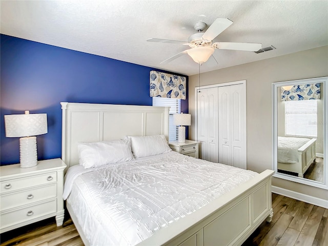 bedroom featuring a textured ceiling, ceiling fan, dark hardwood / wood-style floors, and a closet