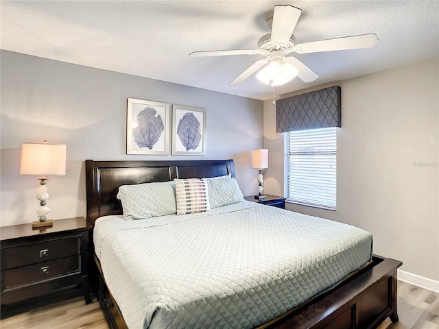 bedroom featuring light wood-type flooring, ceiling fan, and a textured ceiling