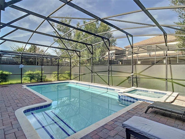 view of pool with a patio, glass enclosure, and an in ground hot tub