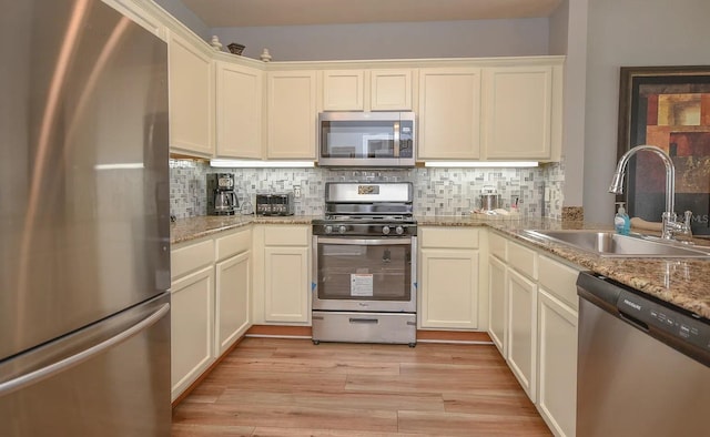 kitchen featuring light hardwood / wood-style flooring, stainless steel appliances, sink, and tasteful backsplash