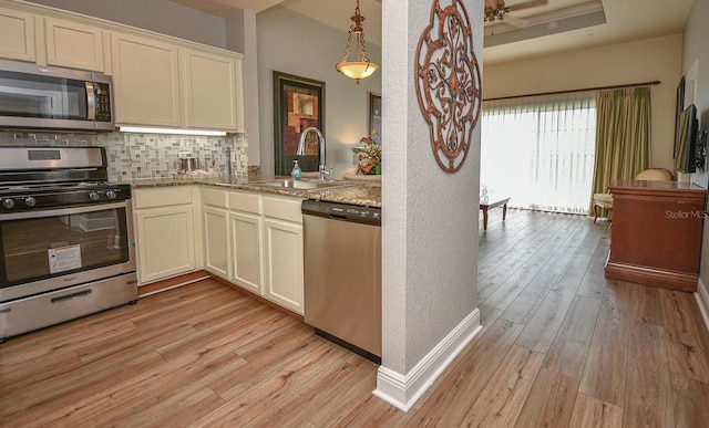 kitchen featuring light wood-type flooring, appliances with stainless steel finishes, tasteful backsplash, and light stone countertops