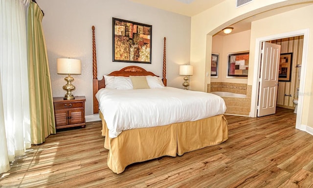 bedroom with wood-type flooring and connected bathroom