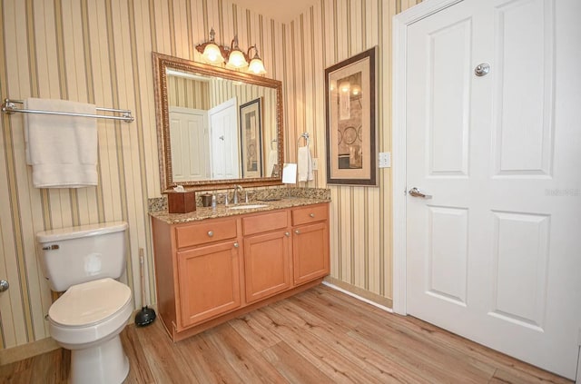 bathroom with vanity, toilet, hardwood / wood-style floors, and wooden walls