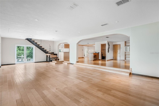 unfurnished living room with a textured ceiling and light hardwood / wood-style floors