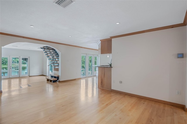 interior space featuring a textured ceiling, light hardwood / wood-style floors, and crown molding