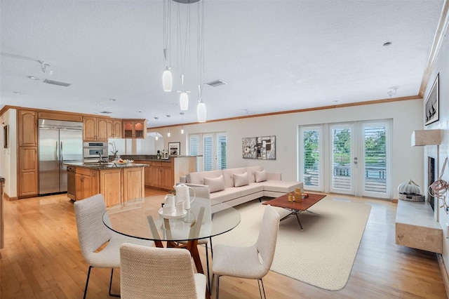 dining room with a textured ceiling, light hardwood / wood-style flooring, and crown molding