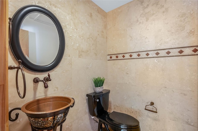 bathroom with tile walls, toilet, and sink