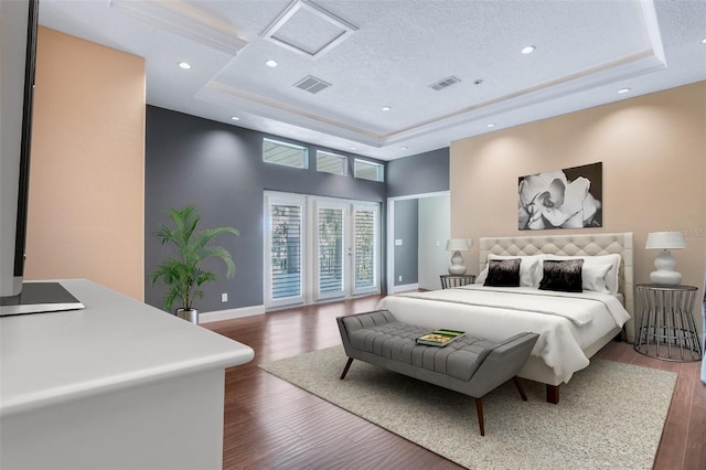 bedroom with a textured ceiling, a raised ceiling, access to outside, and dark wood-type flooring