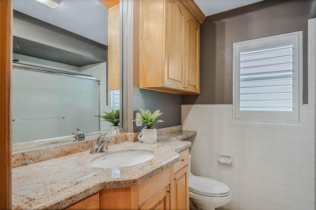 bathroom featuring vanity, tile walls, toilet, and a shower with door