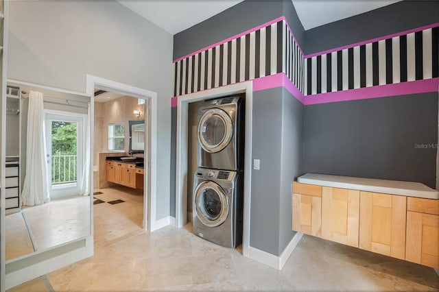 clothes washing area with a high ceiling, stacked washer / dryer, and sink