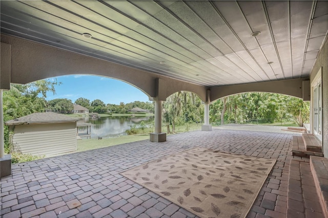 view of patio / terrace featuring a water view and a storage unit