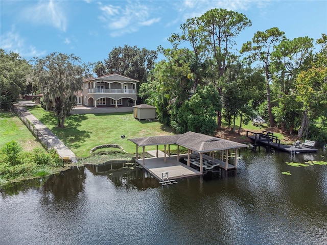 view of dock with a lawn and a water view