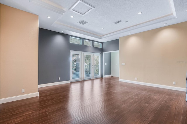 spare room with a textured ceiling, a raised ceiling, and dark hardwood / wood-style floors