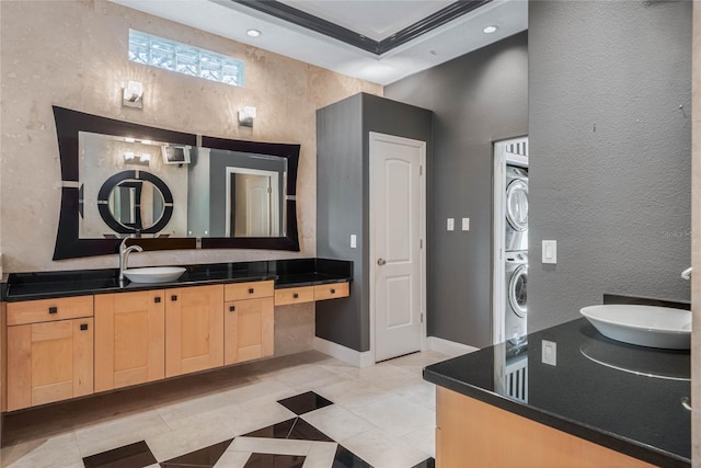 bathroom with vanity, tile patterned floors, ornamental molding, and stacked washing maching and dryer