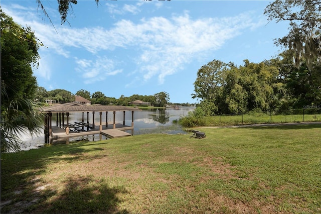 view of dock with a lawn, a water view, and an outdoor fire pit