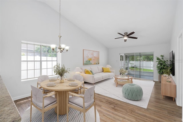 dining area featuring high vaulted ceiling, ceiling fan with notable chandelier, and hardwood / wood-style flooring