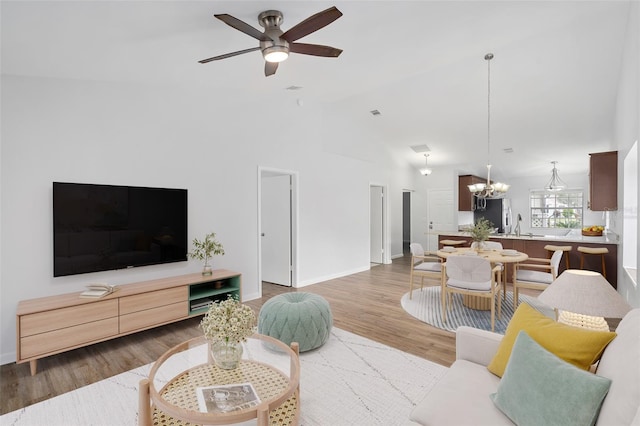 living room featuring ceiling fan with notable chandelier, high vaulted ceiling, hardwood / wood-style floors, and sink