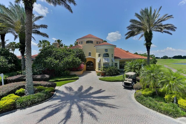 mediterranean / spanish house with a tile roof, curved driveway, and stucco siding