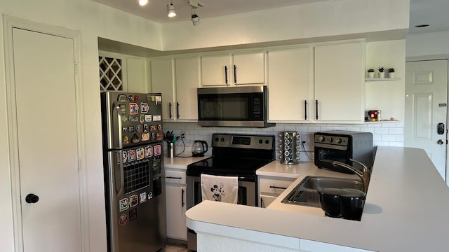 kitchen featuring white cabinets, sink, kitchen peninsula, backsplash, and stainless steel appliances