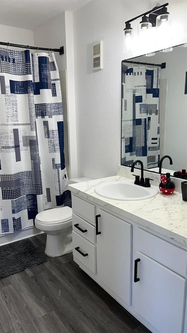 bathroom featuring a shower with shower curtain, wood-type flooring, vanity, and toilet