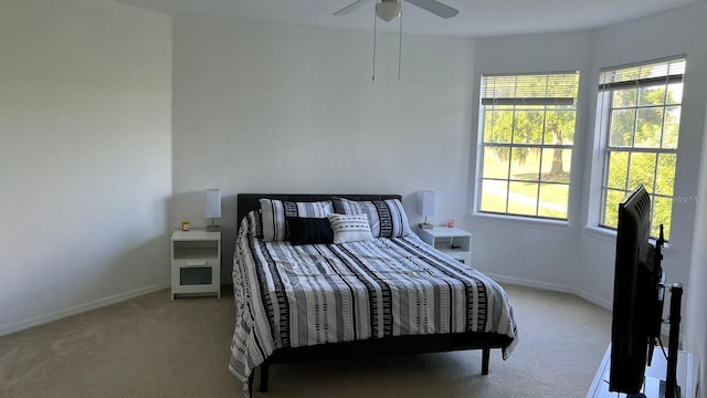 bedroom with ceiling fan, light colored carpet, and multiple windows