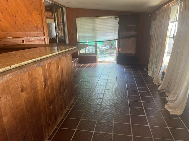 hallway featuring dark tile patterned flooring and wood walls