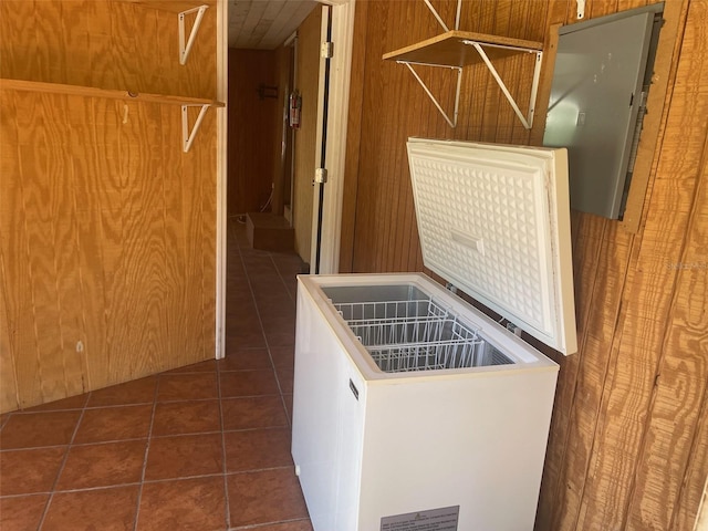 laundry room with dark tile patterned floors and wooden walls