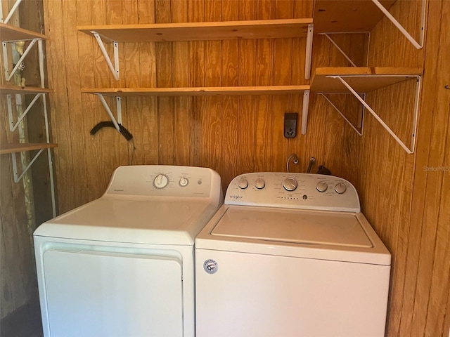 laundry area with wood walls and washing machine and clothes dryer