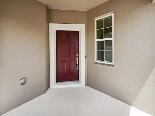 doorway to property featuring stucco siding