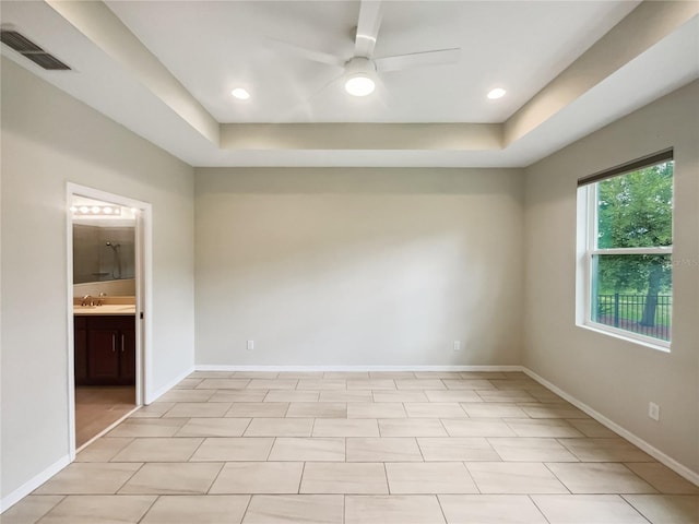 tiled spare room featuring ceiling fan, a raised ceiling, and sink