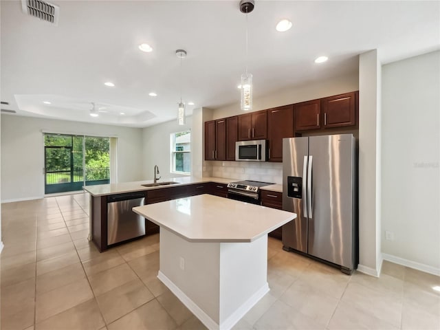 kitchen with hanging light fixtures, appliances with stainless steel finishes, sink, a raised ceiling, and kitchen peninsula