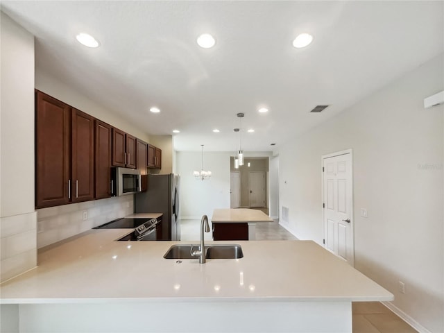 kitchen featuring pendant lighting, appliances with stainless steel finishes, kitchen peninsula, sink, and a chandelier