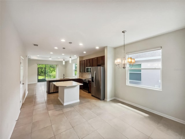 kitchen with a center island, appliances with stainless steel finishes, sink, pendant lighting, and dark brown cabinetry