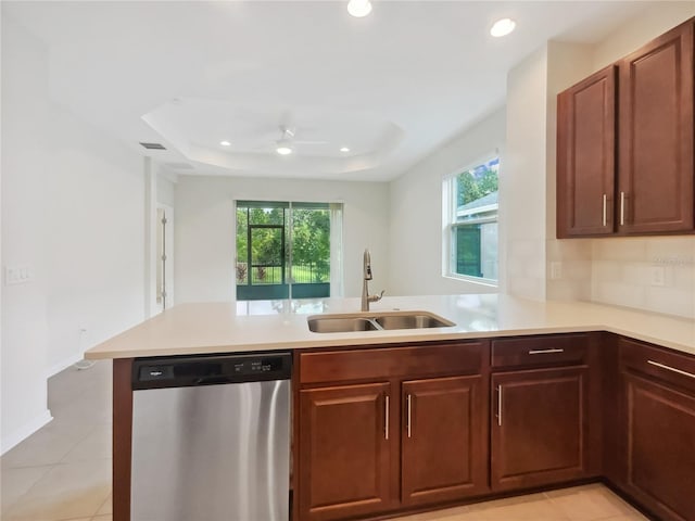 kitchen featuring a peninsula, plenty of natural light, dishwasher, a sink, and a tray ceiling