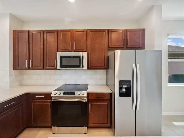 kitchen featuring light tile patterned floors, backsplash, and stainless steel appliances