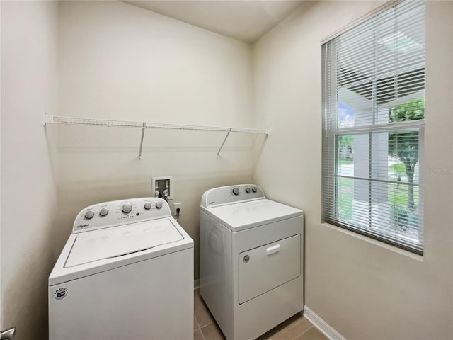 clothes washing area featuring laundry area, light tile patterned flooring, separate washer and dryer, and baseboards