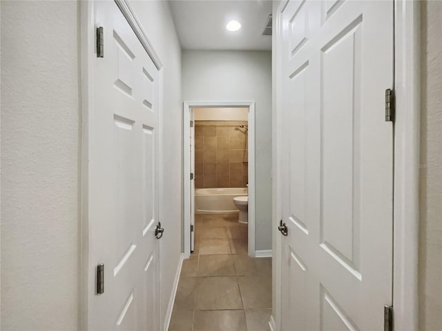 hall featuring light tile patterned floors and baseboards