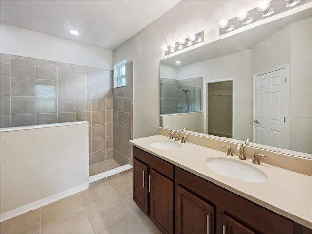 bathroom featuring tile patterned flooring, a tile shower, and vanity