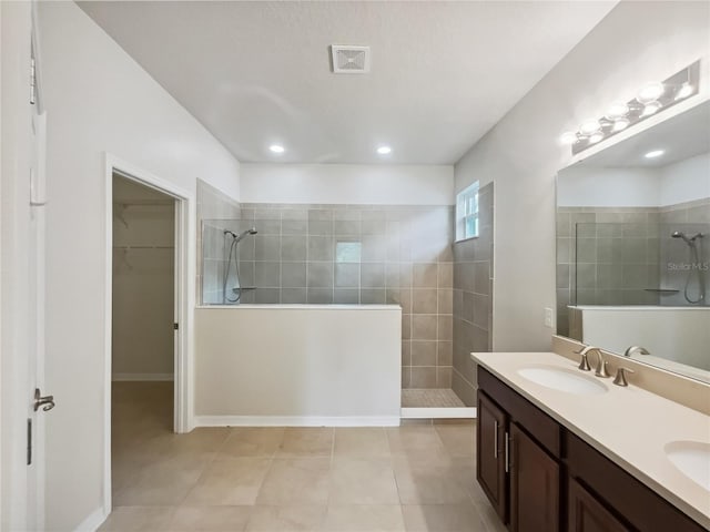 bathroom with vanity, a tile shower, and tile patterned flooring