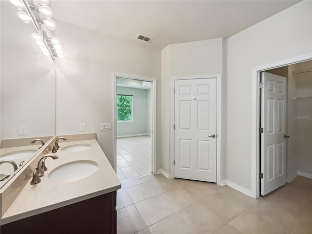 full bath with tile patterned flooring, visible vents, double vanity, and a sink