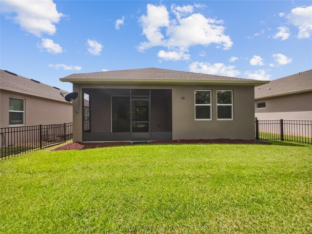 rear view of property with a yard and a sunroom