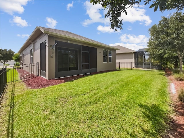 rear view of house featuring a sunroom, a lawn, a fenced backyard, and stucco siding