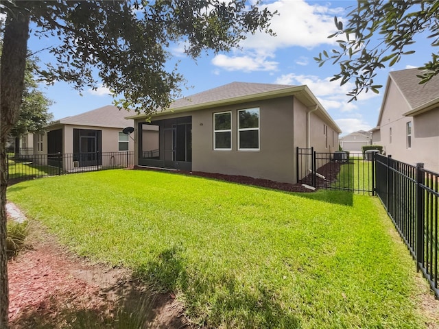 rear view of house featuring stucco siding, a lawn, and a fenced backyard